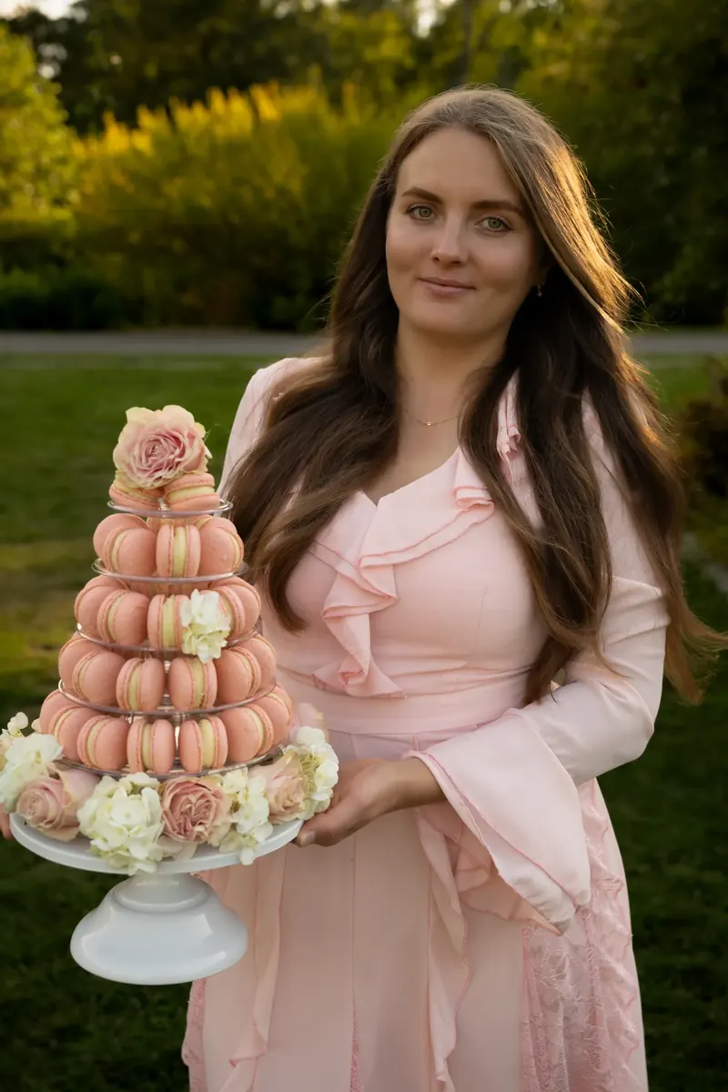 Anastasiia of a Ukrainian bakery in Boston with macarons, cake, and a pink gift box
