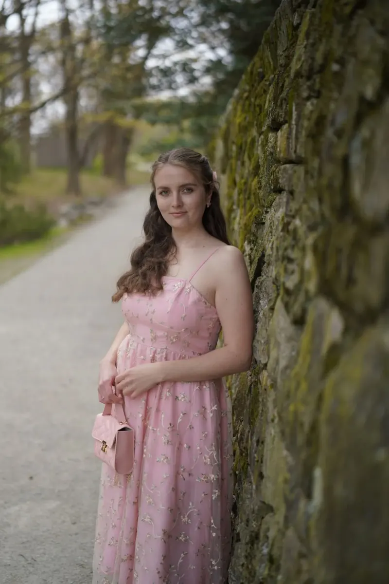 Anastasiia, founder of a Ukrainian bakery in Boston, standing beside a stone wall
